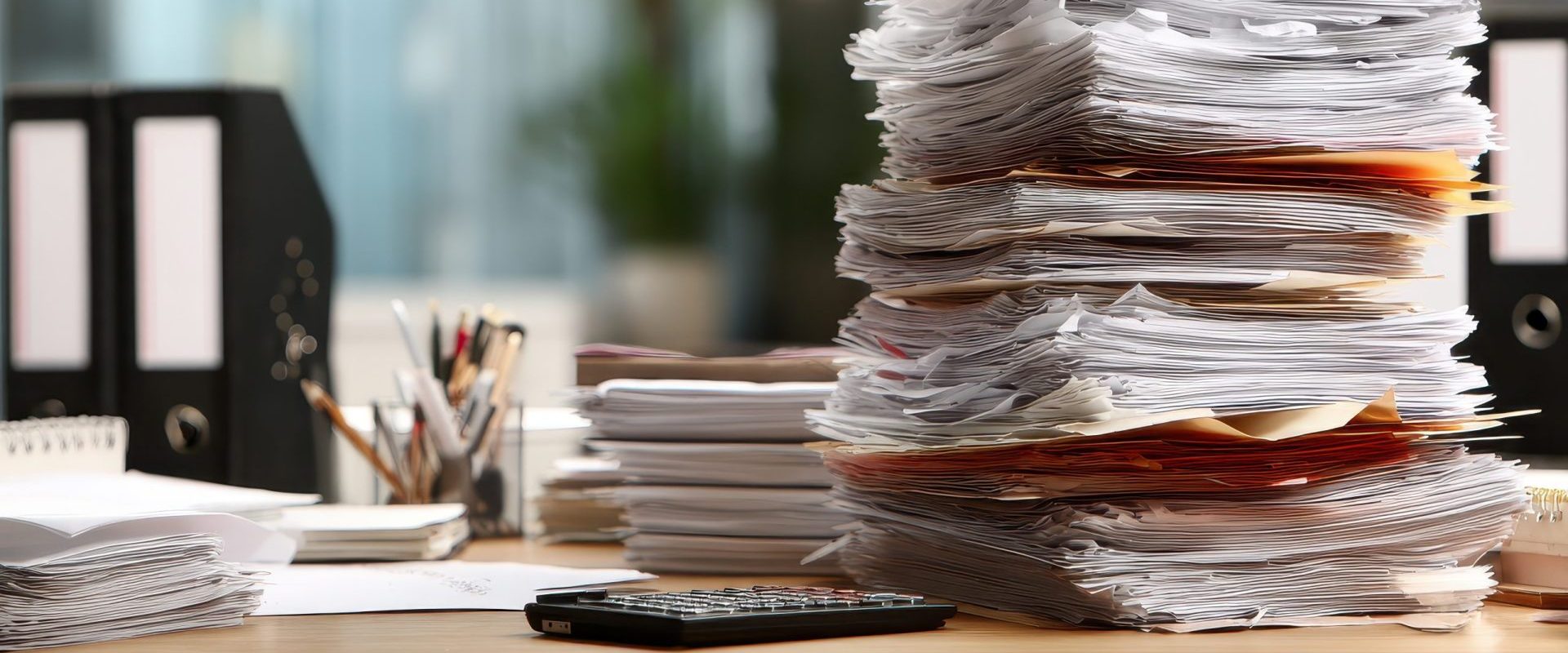 Stack of overdue paperwork and receipts piled on an office desk.
